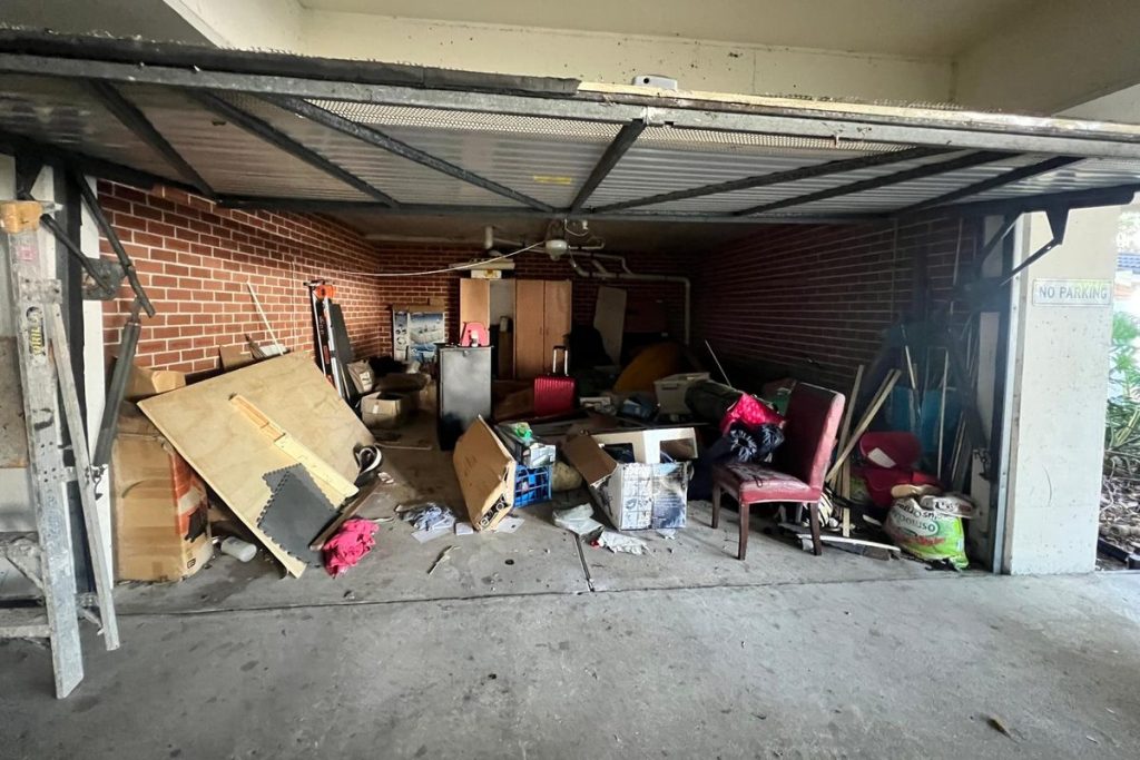 Cluttered garage full of furniture and boxes before a Rubbish Runners clear-out