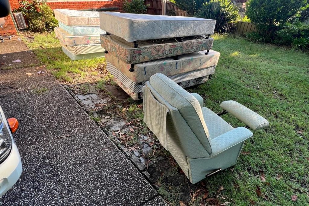 Old mattresses and an armchair on a front lawn ready for rubbish removal