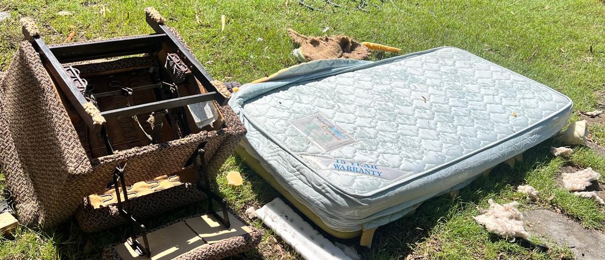 Old armchair frame and mattress on a lawn for household rubbish removal